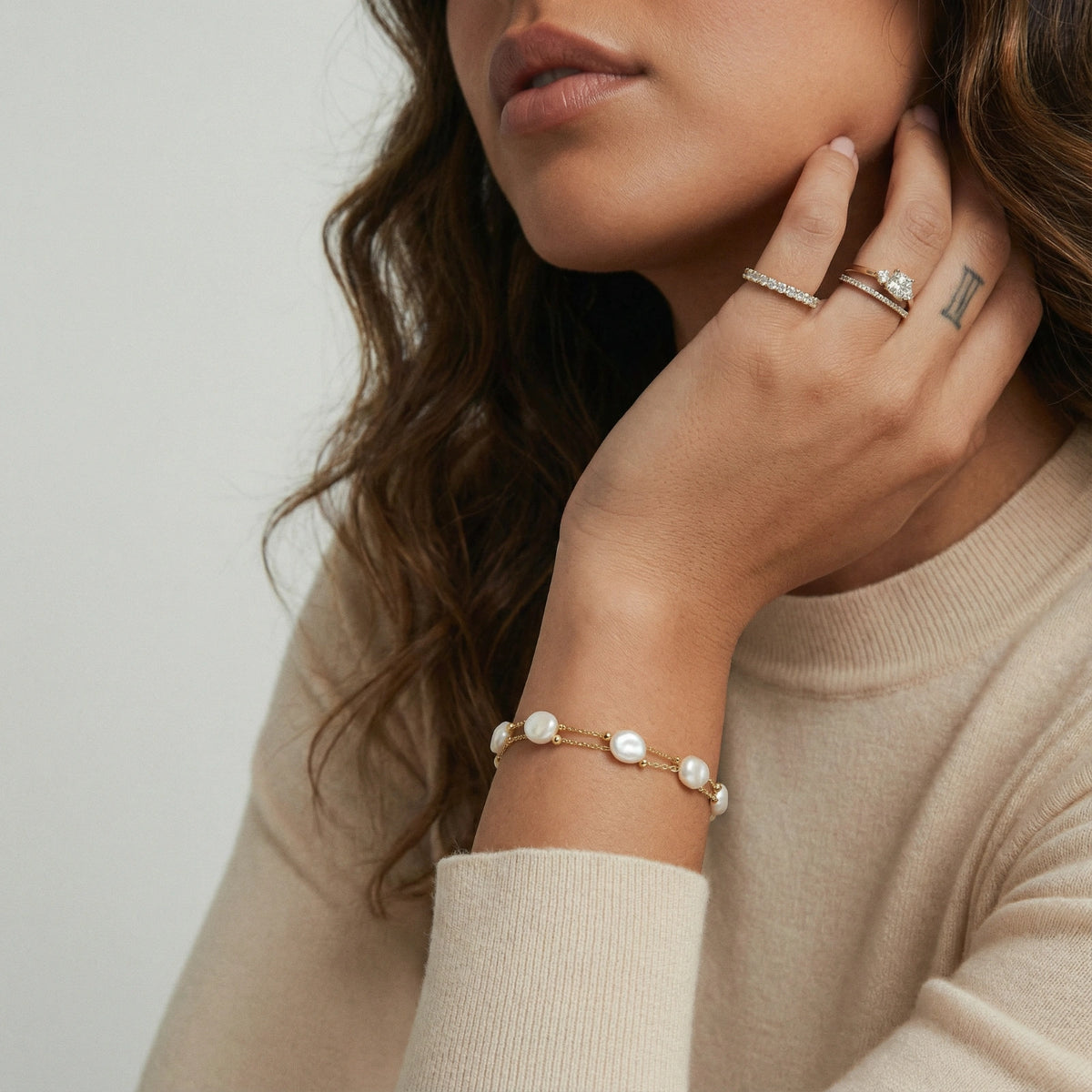 Woman wearing baroque pearl layered bracelet in 18K gold vermeil