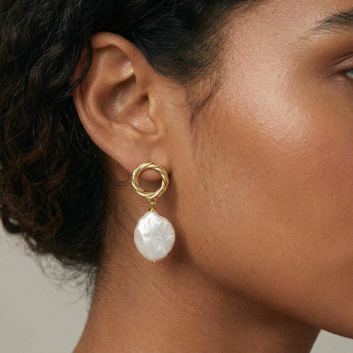 Woman wearing baroque pearl drop earrings with 18K gold vermeil twisted studs